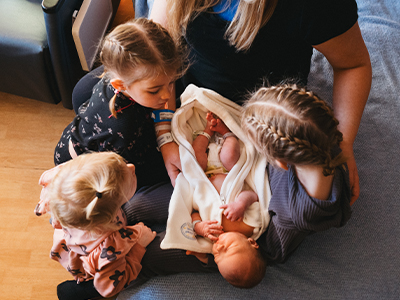 Image of sisters meeting new baby sibling